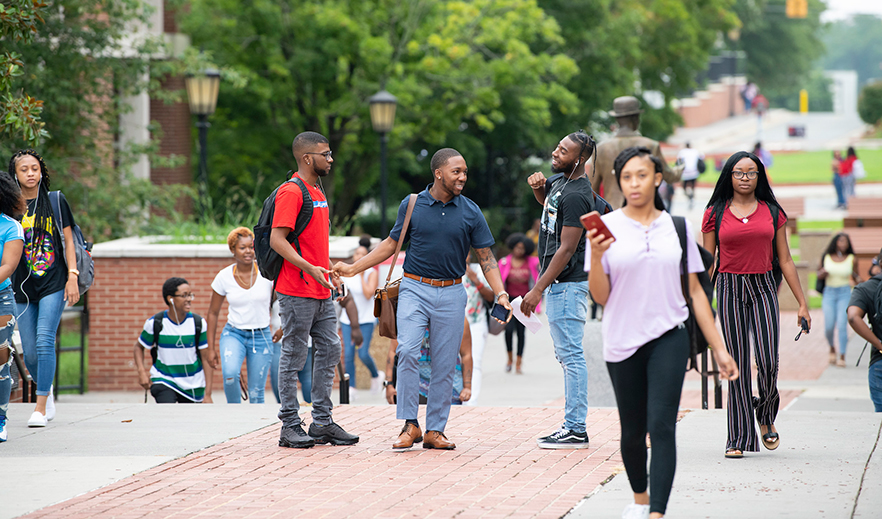 students walk near the S.G. Atkins statue on campus