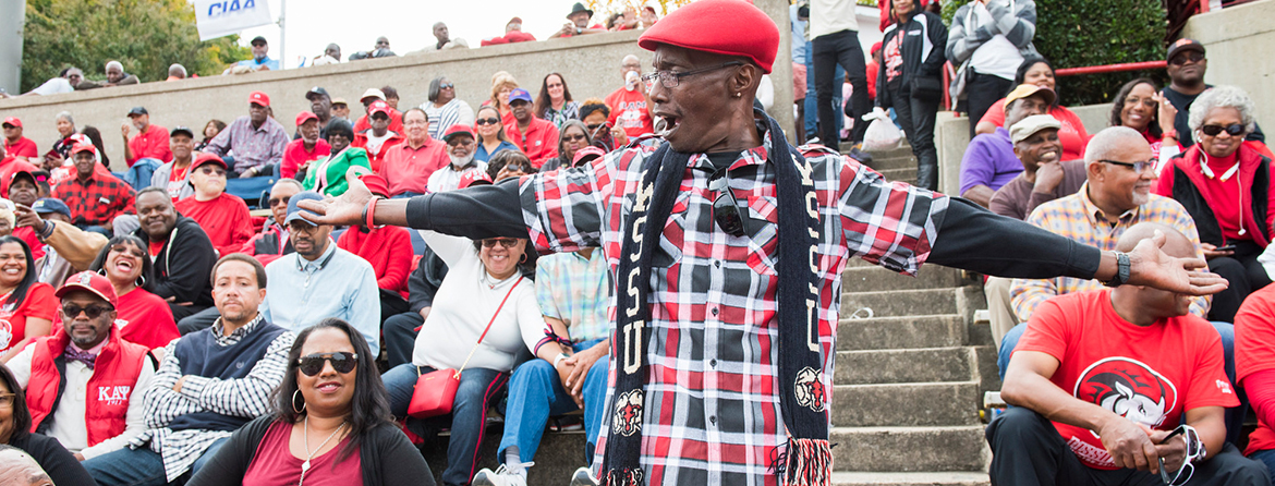 Man in WSSU red stands out during a football game in the stands at Bowman Gray Stadium