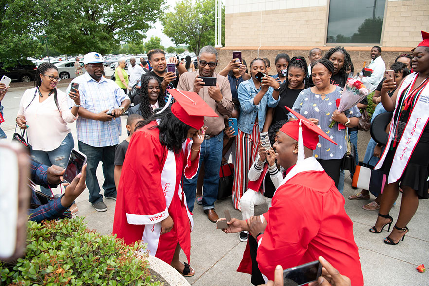 Wearing red cap and gowns, graduate holds a jewelry box