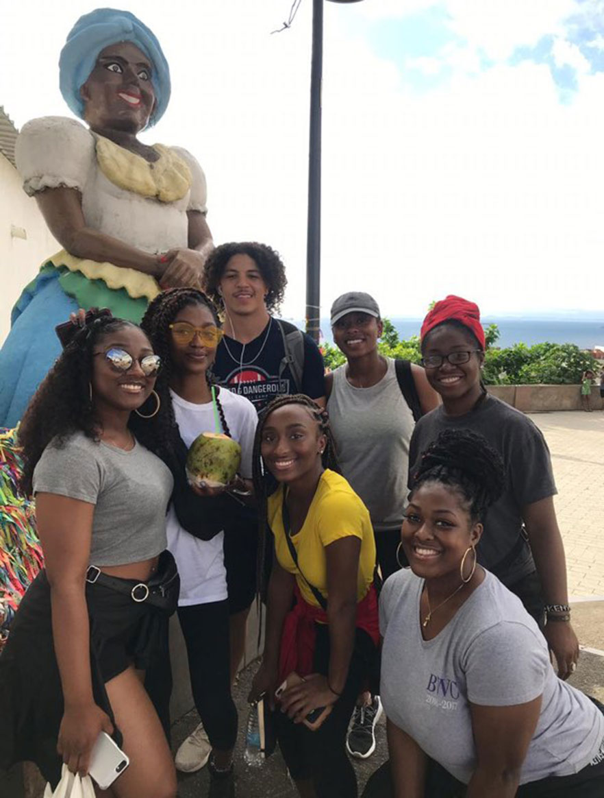 7 students stand beside statue in Brazil