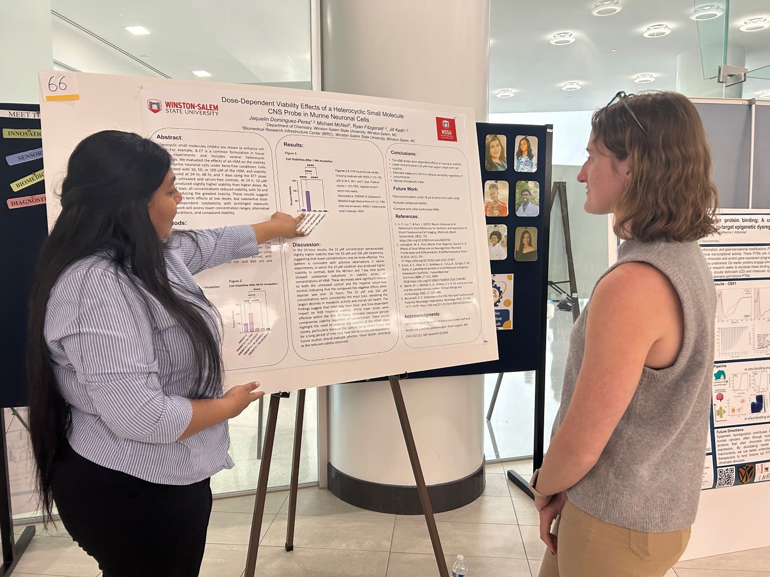 Student points to her research poster while presenting to a judge