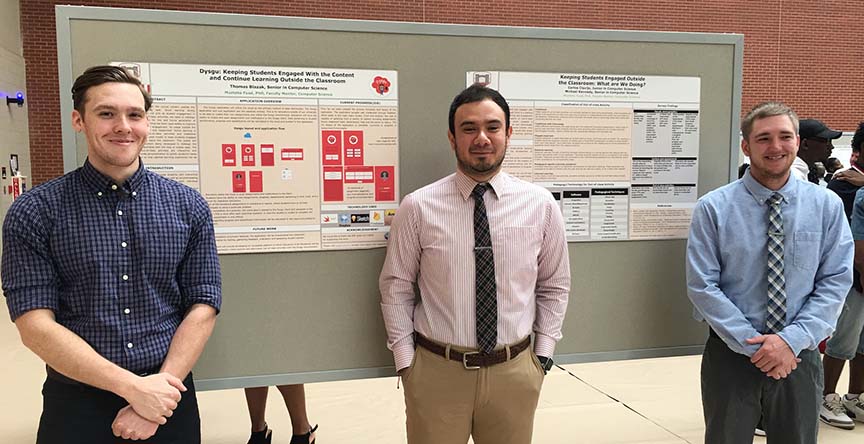 Three research students presenting a poster during Scholarship Day on-campus.