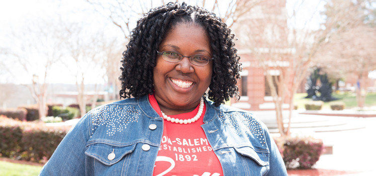 a woman with glasses, smiling.