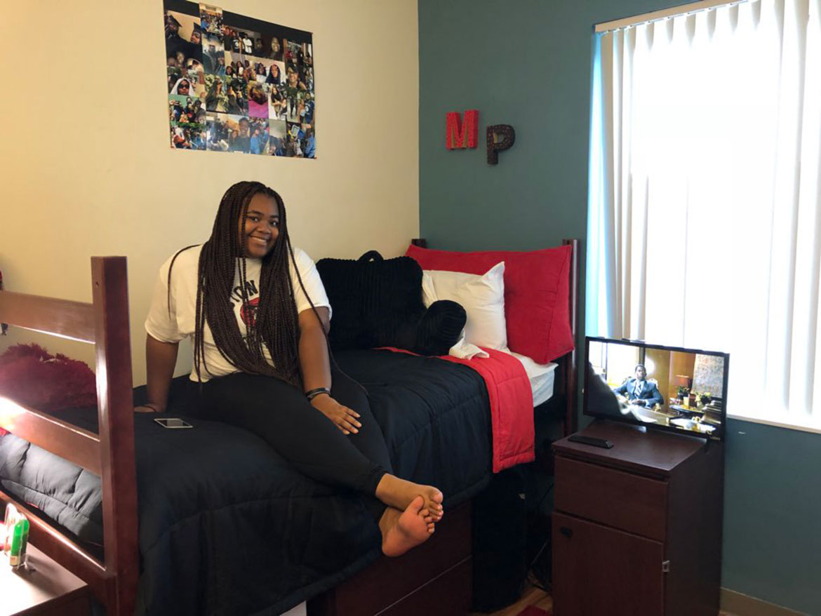 Girl sitting on bed in residence hall room